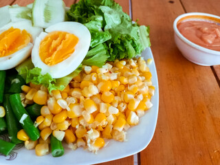 Healthy Cobb Salad Style Plate with Boiled Eggs, Corn, and Green Beans on a Wooden Table