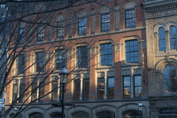 Fototapeta premium exterior of Dixon/Beardmore Block (section with brick at 45-49 Front St E) projecting sign of Winners Dept Store, sunset, Toronto