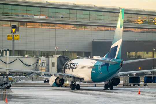 Calgary, Alberta, Canada. Dec 12, 2025. Rear view of a WestJet Boeing 737 commercial airplane parked at a snowy gate jetway at the Calgary International Airport (YYC) during winter.