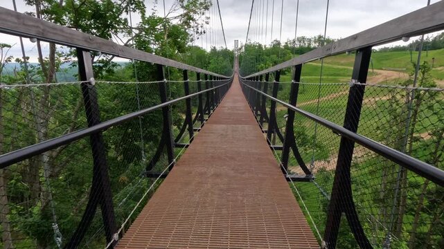Point of view from a person walking along a Suspension Bridge High in the Sky. The bridge connects two mountains with views of the valley below. Located in Northern Michigan, USA.