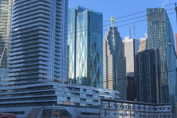 Fototapeta premium cluster of modern office buildings and residential skyscrapers viewed from Queens Quay E (incl: The Prestige at Pinnacle One Yonge, CIBC Square, TD Canada Trust Tower, First Canadian Place, and L-Towe