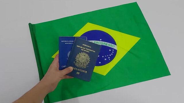 Hand holding Brazilian Work Card and Passport with Brazil flag in white background