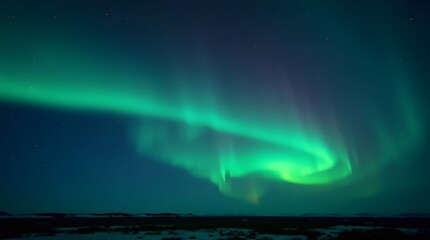 Naklejka premium Mesmerizing display of the Aurora Borealis illuminating the dark night sky over a serene, snow-covered winter landscape, showcasing nature's vibrant light show