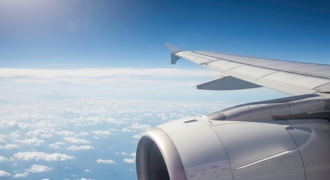 A view from an airplane window, showcasing the wing and engine of a jet plane against a backdrop of clouds and a clear blue sky.