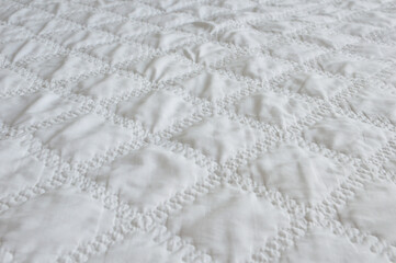 Obraz premium A white quilt with a diamond-shaped, textured stitching pattern.