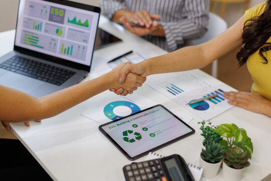 Close up of business people shaking hands over ESG strategic commitment workshop, SDGs report, global warming, green finance investment eco friendly and net zero waste in boardroom training building.