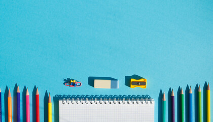 Colorful school supplies arranged neatly on a blue background with a blank notebook for notes and drawings