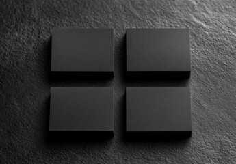 Four matte black stacked rectangular cards arranged in a two by two grid on a textured dark surface, minimalist moody elegant atmosphere