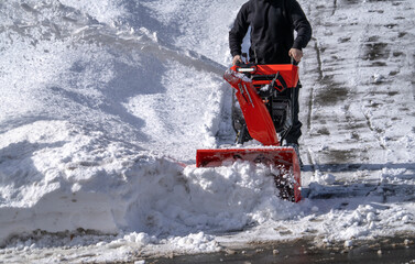 man removing snow on the driveway of the house by snow blower
