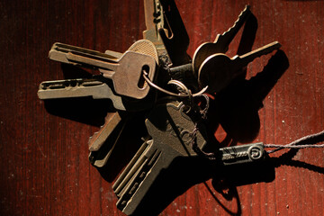 Bunch of old keys and rusty metal on a dark wooden table in strong sunlight. Concept of security,...