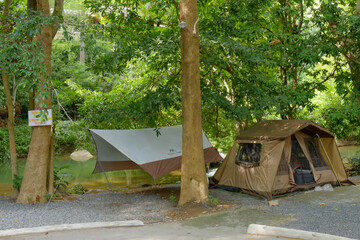 Riverside Campsite with Tent and Tarp Under Forest Canopy