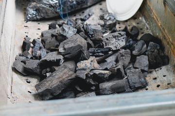 Pile of natural wood charcoal pieces ready inside a metal barbecue grill