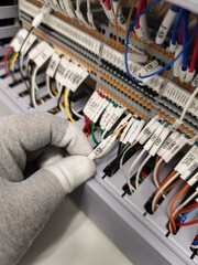 Gloved Hand Holding Labeled White Wire in Electrical Terminal Panel