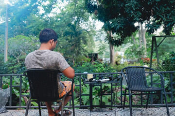 Man enjoying morning coffee at outdoor garden caf&eacute; with lush greenery