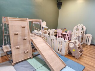 Indoor kids play area with wooden climbing gym and colorful toys
