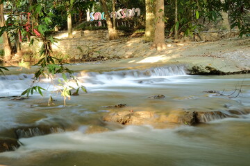 Small waterfall in forest stream with colorful signage