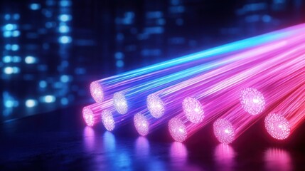 Close-up of glowing fiber optic cables emitting blue and pink light on dark reflective surface with blurred lights in the background