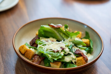 vegetable greens salad with biscuits crispy bacon ground butter and salad dressing in plate or dish on brown wooden table and top view for vegetables diet healthy food and breakfast in restaurant