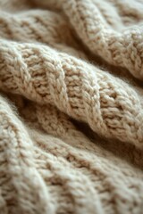Close-up view of soft beige knitted fabric with braided cable patterns creating a cozy and warm texture