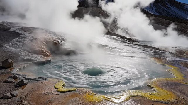Bubbling geothermal spring releasing plumes of white steam amidst mineral deposits and rugged terrain