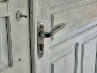 Close-up of old white wooden door with metal handle and keyhole detail