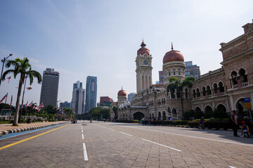 Kuala Lumpur, Malaysia - August 31, 2024: The Sultan Abdul Samad Building, a historical landmark with Moorish architecture and a clock tower, next to a wide empty road and modern skyscrapers.