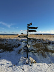 Directional sign and the iconic B&aacute;r&eth;ur Sn&aelig;fells&aacute;s Statue, a landmark on the Sn&aelig;fellsnes Peninsula, with sweeping views of the ocean, mountains, and dramatic coastal cliffs in western Iceland.