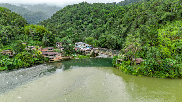 A stunning aerial view of Agua Clara, Valle del Cauca, showcasing lush greenery, a winding river, and quaint houses nestled in nature.