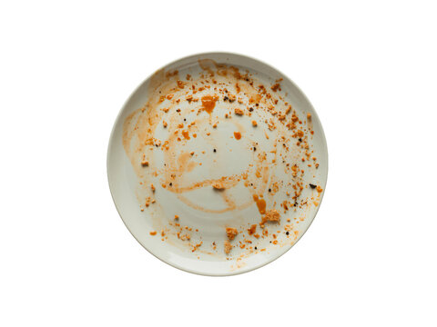 An empty, white plate is shown with various food crumbs and sauce smears left after a meal.