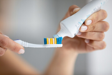 Dental care routine. Cropped close up young female hands squeezing toothpaste on toothbrush before cleaning teeth. Daily oral hygiene caries cavity prevention teeth whitening gums protection concept