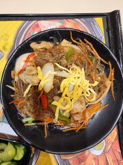 Savory Stir-Fried Noodles With Chicken, Vegetables, And Egg Garnish On A Black Plate
