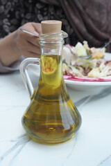 Oil bottle placed on table with plate of food nearby