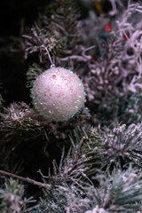 Close-up of a beautifully decorated ornament hanging on a artificial Christmas tree.