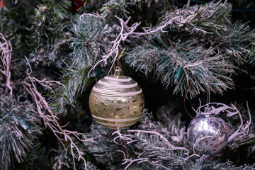 Close-up of a beautifully decorated ornament hanging on a artificial Christmas tree.