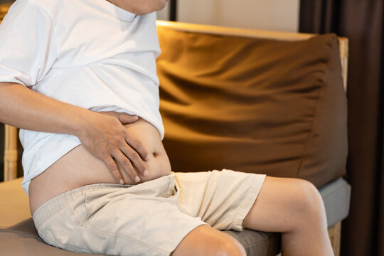 Middle-aged man suffering from stomach ache or digestive problems,holding his abdomen in discomfort,risk of chronic diseases,Concept of indigestion,bloating,gut health issues,unhealthy eating habits