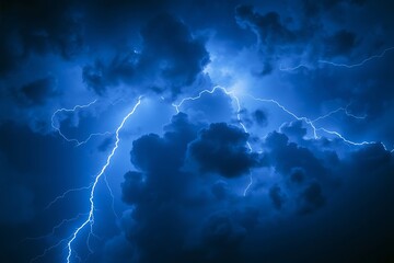 Electric blue lightning rips through dark storm clouds at night, creating a dramatic atmospheric background showcasing power, energy, danger, and intense weather in a sky.