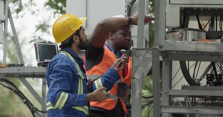 Telecom engineer and technician inspect communication equipment during network maintenance and upgrade operation. Infrastructure inspection, troubleshooting, cable management for reliable connectivity
