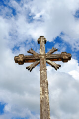 Old wooden cross on a blue cloudy sky background