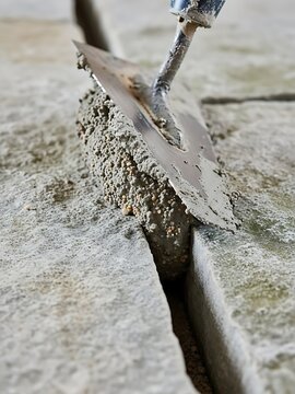 Carefully filling joints between paving stones with mortar using a trowel