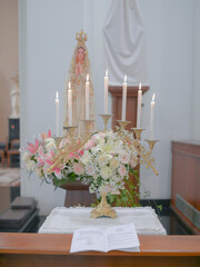 candles and flowers in church with the Virgin Mary in the background