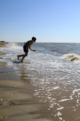 Boy playing in azov sea waves on sandy beach