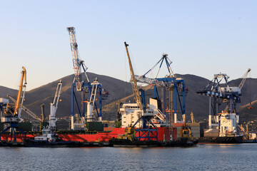 Obraz premium Cargo vessel docked at industrial port with large cranes