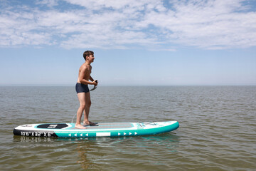 Boy standing on paddleboard in Azov sea