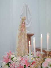 candles and flowers in church with the Virgin Mary in the background