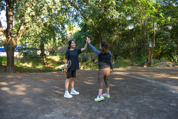 lifestyle moment of an active mother and daughter spending quality time together after outdoor exercise at a stadium. They play skateboarder
