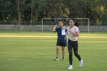 Obraz premium Two people exercising outdoors, jogging together on a green grass field during a sunny afternoon.