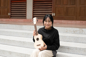 A natural portrait of a teenage girl holding a ukulele while sitting on outdoor steps, symbolizing creativity, youth, music learning, confidence, and artistic self-expression.
