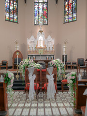 bridal chairs in a church with an altar behind them
