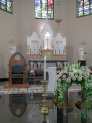 candles and flowers with an altar in the background in a church