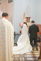 a bride and groom are praying with the priest behind them
